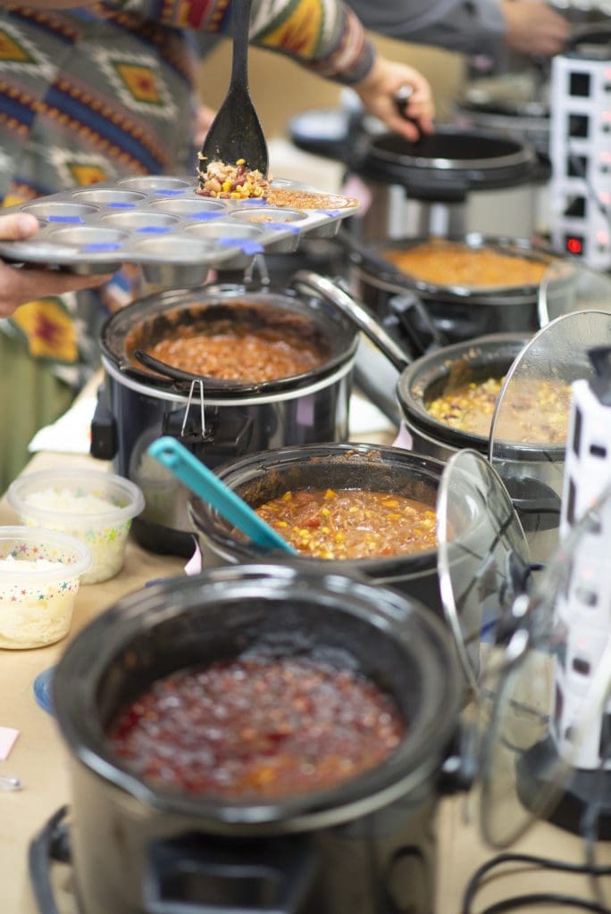 Close-up picture of crockpots with various chili dishes in a chili cook-off contest