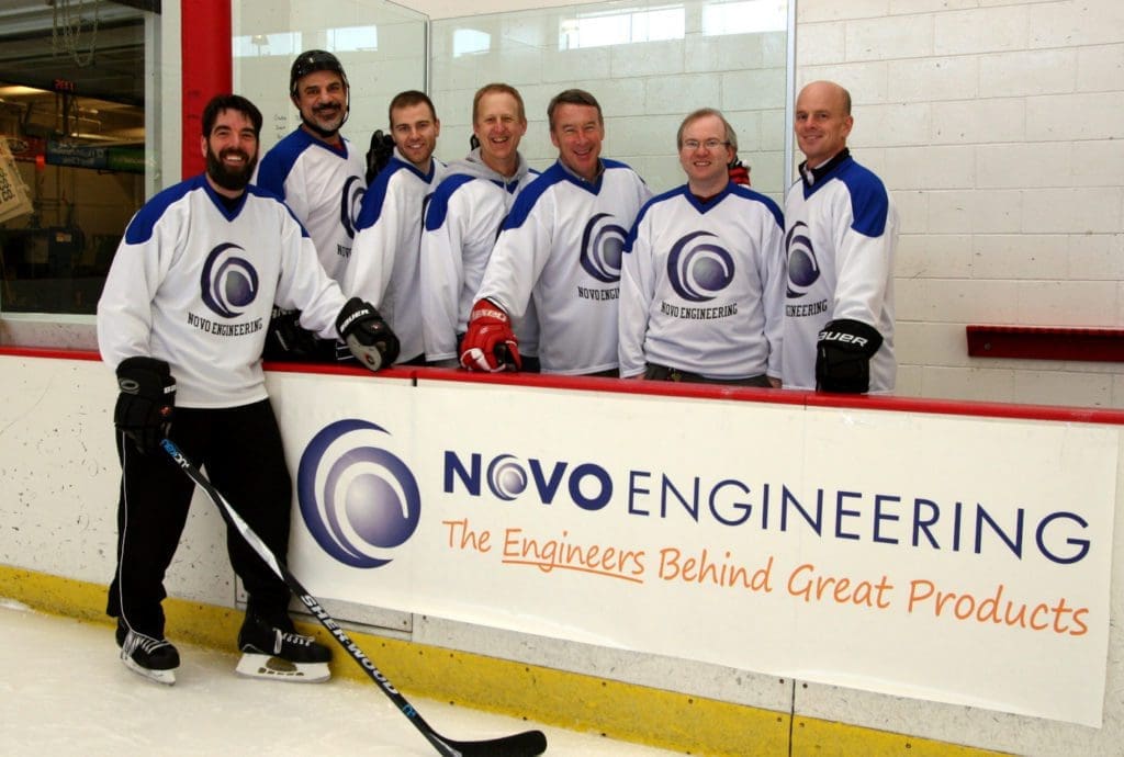 NOVO engineer team in Minneapolis playing ice hockey with company banner in foreground